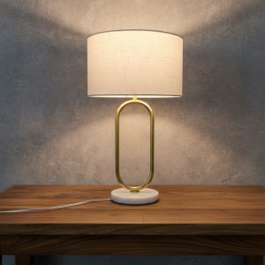 Lámpara de mesa moderna de 52 cm de altura con pantalla cilíndrica blanca de 35 cm de diámetro, cuerpo ovalado dorado y base de mármol claro.